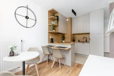 a kitchen with white cabinets and a white table and chairs at Walerego Sławka Cosy Studio by BookingHost in Kraków