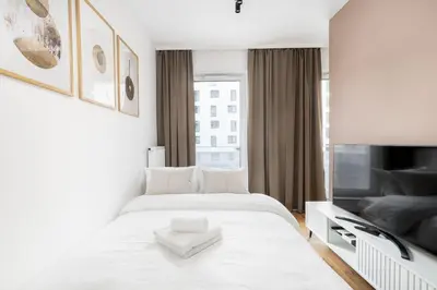a white bedroom with a bed and a tv at Walerego Sławka Cosy Studio by BookingHost in Kraków