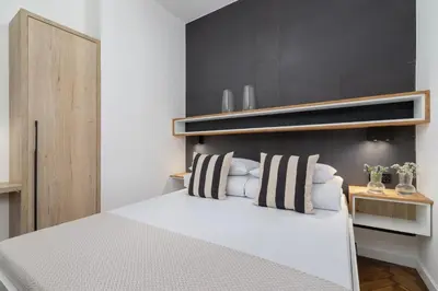 a bedroom with a white bed with striped pillows at Studio Apartment - Dietla 21 street in Kraków