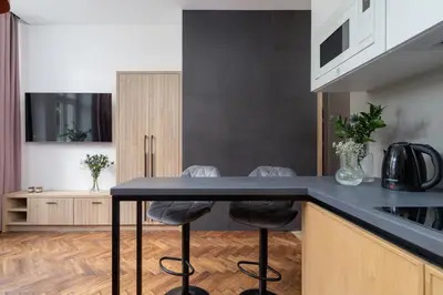 a kitchen with a black counter and stools at Studio Apartment - Dietla 21 street in Kraków