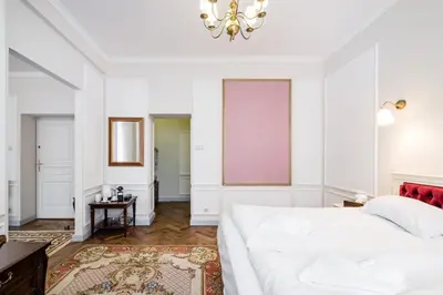 a bedroom with a white bed and a pink board on the wall at Househost Apt: Starowiślna 75/3/1 in Kraków