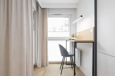a room with a desk and a chair next to a window at Lema 19 Uniqe Apartment in Krakow with Garden Air Conditioning Parking near Tauron Arena by Renters Prestige in Kraków