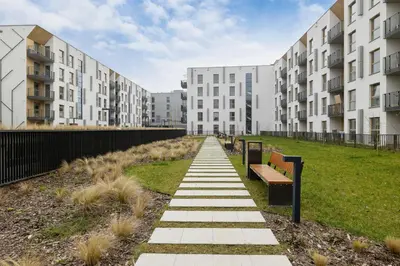 a walkway with benches in front of apartment buildings at Lema 19 Uniqe Apartment in Krakow with Garden Air Conditioning Parking near Tauron Arena by Renters Prestige in Kraków