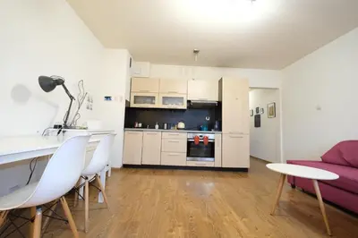a kitchen and living room with white cabinets and a purple couch at Przystań Dolnych Młynów in Kraków
