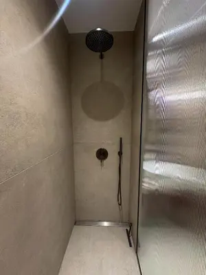 a shower in a bathroom with a metal wall at Tu - Lum Apartament in Kraków