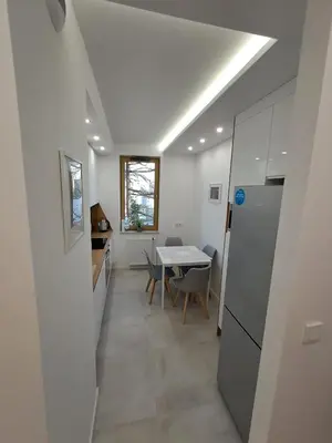 a kitchen and dining room with a table and a refrigerator at APARTAMENTY HEMMA ORAWSKA 14 in Kraków