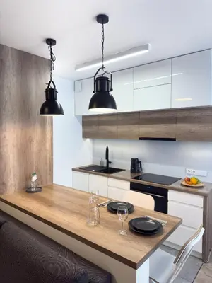 a kitchen with a wooden table and black pendant lights at Industro Art Zablocie - Balcony - WiFi 1GB - 55