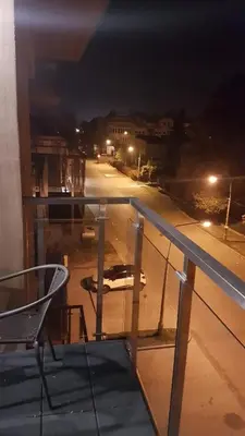a chair on a balcony with a street at night at Apartament DeLuxe 4 in Oświęcim