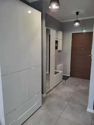 a kitchen with white cabinets and a wooden door at Apartament DeLuxe 4 in Oświęcim
