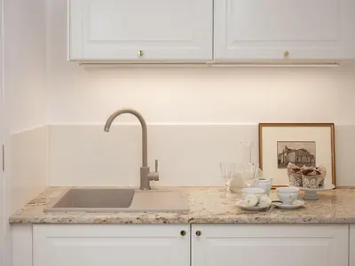 a kitchen counter with a sink and white cabinets at AVANTI Home in Kraków