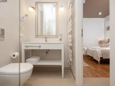 a bathroom with a sink and a toilet and a bed at AVANTI Home in Kraków