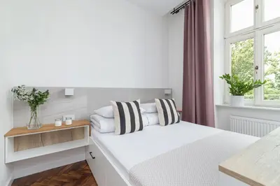 a white bedroom with a bed and a window at Kazimierz Area - Dietla 21 street in Kraków