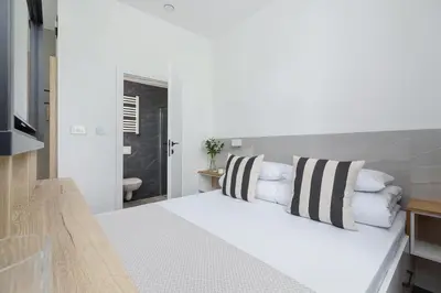 a bedroom with a white bed with striped pillows at Kazimierz Area - Dietla 21 street in Kraków