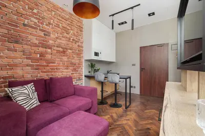 a living room with a purple couch and a brick wall at Kazimierz Area - Dietla 21 street in Kraków