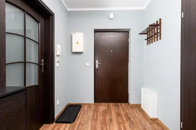 a hallway with a brown door and a wooden floor at Podgórze Standard Studio by BookingHost in Kraków