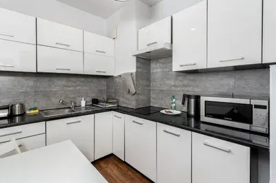 a white kitchen with white cabinets and a microwave at Podgórze Standard Studio by BookingHost in Kraków