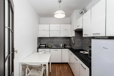 a kitchen with white cabinets and a white table at Podgórze Standard Studio by BookingHost in Kraków