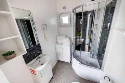 a white bathroom with a shower and a sink at Fantazja Resort Zator in Zator