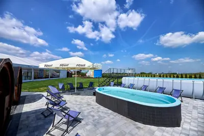 a pool with chairs and an umbrella on a patio at Fantazja Resort Zator in Zator