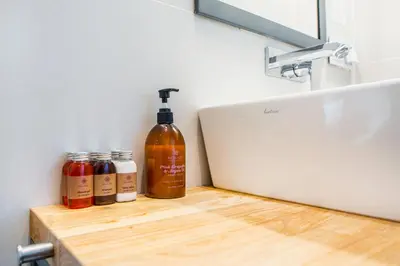 a bottle of alcohol sitting on a counter next to a sink at Tomasza 26 Old Town Suites in Kraków