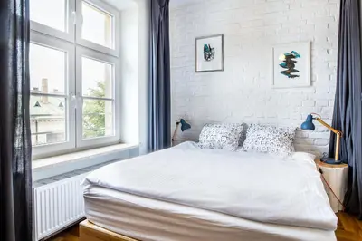 a white bedroom with a bed and a window at Tomasza 26 Old Town Suites in Kraków
