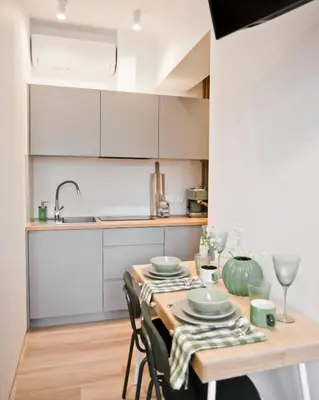 a kitchen with a wooden table with chairs and a sink at Balaton Apartamenty in Trzebinia