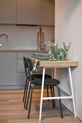 a wooden table with black chairs and a kitchen at Balaton Apartamenty in Trzebinia