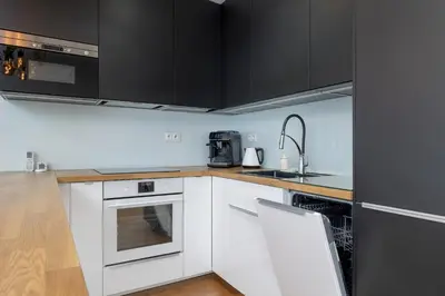 a kitchen with white appliances and black cabinets at Ślusarska Modern Apartment with Balcony & Parking Cracow Zabłocie by Renters Prestige in Kraków