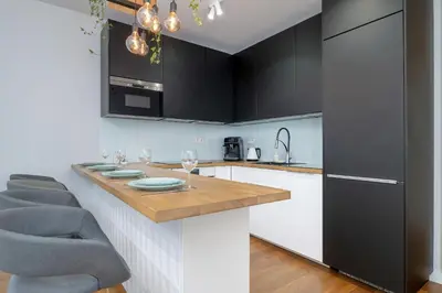a kitchen with black cabinets and a wooden counter top at Ślusarska Modern Apartment with Balcony & Parking Cracow Zabłocie by Renters Prestige in Kraków