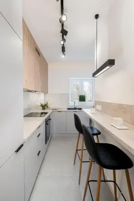 a kitchen with white cabinets and black chairs at Royal Center Apartments in Kraków