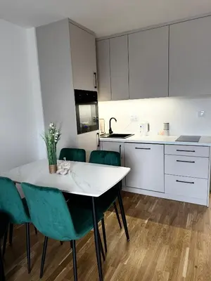 a kitchen with a white table and green chairs at Apartament na Orkana in Rabka-Zdroj
