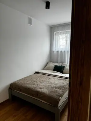 a bed in a white room with a window at Apartament na Orkana in Rabka-Zdroj