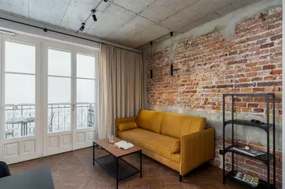 a living room with a yellow couch and a brick wall at San Sebastian - beauty&silence in Kraków