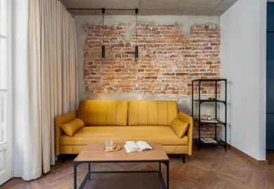a yellow couch in a room with a brick wall at San Sebastian - beauty&silence in Kraków