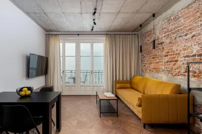 a living room with a yellow couch and a brick wall at San Sebastian - beauty&silence in Kraków