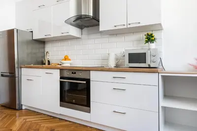 a kitchen with white cabinets and a microwave at Vistula River Apartment in Kraków