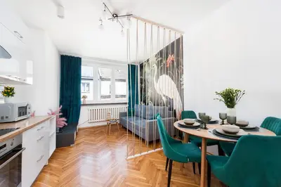 a kitchen and dining room with a table and green chairs at Vistula River Apartment in Kraków