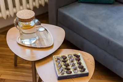 a tray of chocolates and a bottle of honey on two tables at Vistula River Apartment in Kraków