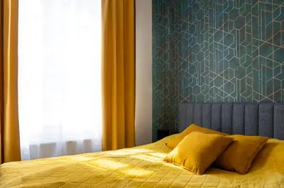 a bedroom with a bed with yellow sheets and a blue wall at Grzegórzki Studio - Main Station & Parks nearby - by Rentujemy in Kraków