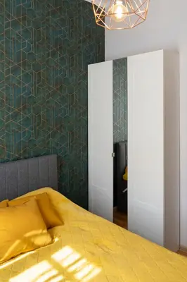 a bedroom with a yellow bed with a green wall at Grzegórzki Studio - Main Station & Parks nearby - by Rentujemy in Kraków