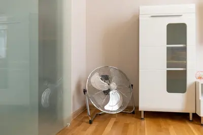 a white fan in a room next to a white cabinet at Grzegórzki Studio - Main Station & Parks nearby - by Rentujemy in Kraków