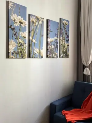four paintings on a wall with a blue couch at Krakow Apartments & Rooms in Kraków