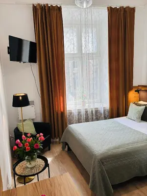 a bedroom with a bed and a window with a vase of flowers at Krakow Apartments & Rooms in Kraków