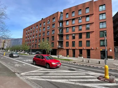 a red car parked at a crosswalk in front of a building at Angel City Apartament in Kraków