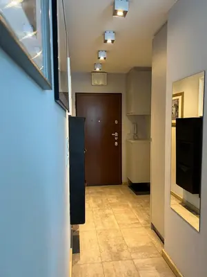 a hallway with a brown door and a kitchen at Angel City Apartament in Kraków