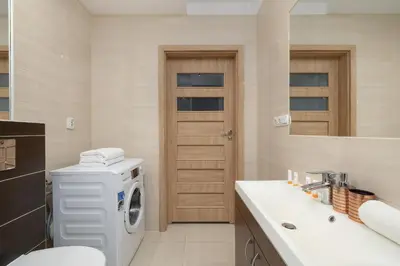 a bathroom with a washing machine and a sink at Podgórze Air-Conditioned Family Apartment with Parking by Noclegi Renters in Kraków