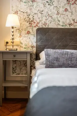 a bedroom with a bed and a table with a lamp at Vintage Bracka Apartment in Kraków