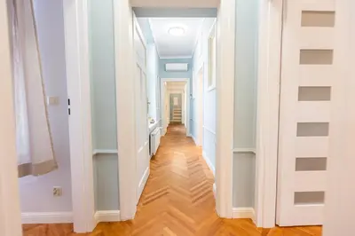 a hallway with white walls and a hard wood floor at Vintage Bracka Apartment in Kraków