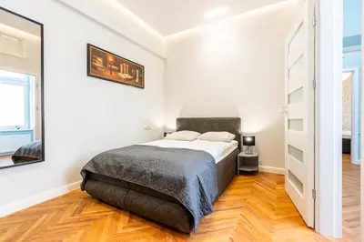 a bedroom with a large bed in a white room at Vintage Bracka Apartment in Kraków