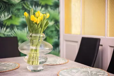 a glass vase with yellow flowers in it on a table at Vintage Bracka Apartment in Kraków